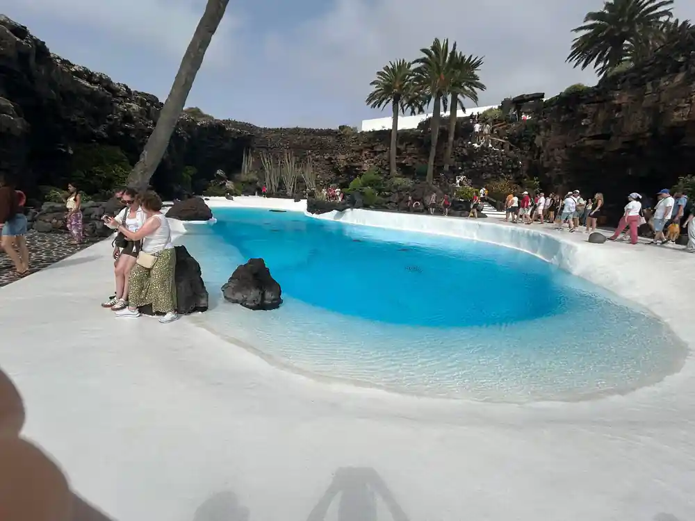 Bright turquoise pool in volcanic crater with palm trees