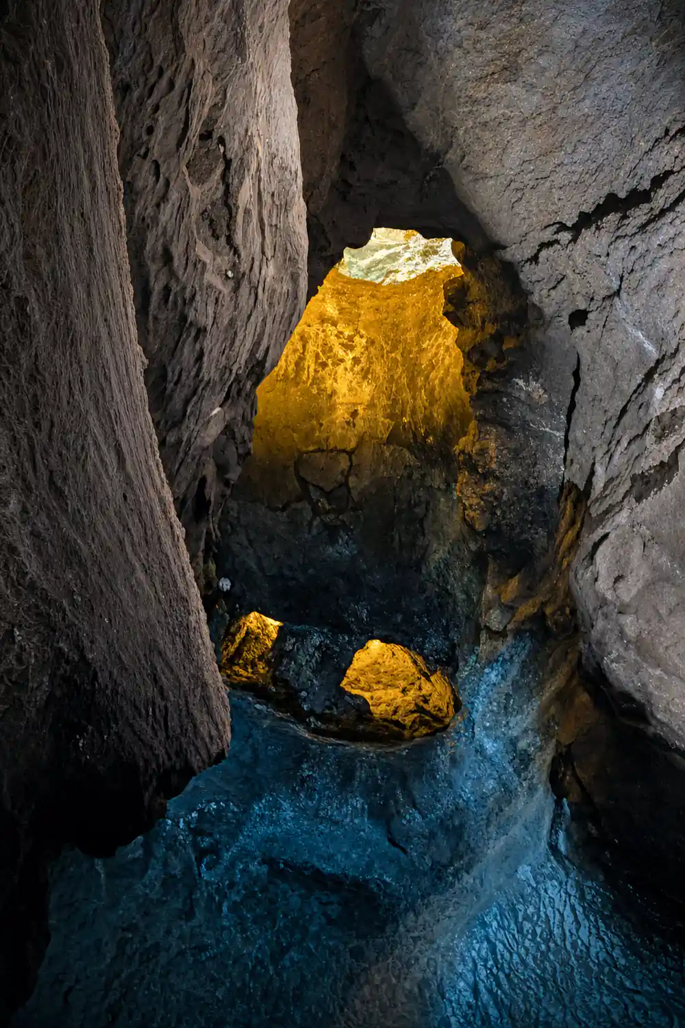 Bright yellow and turquoise mineral deposits in dark stone cave