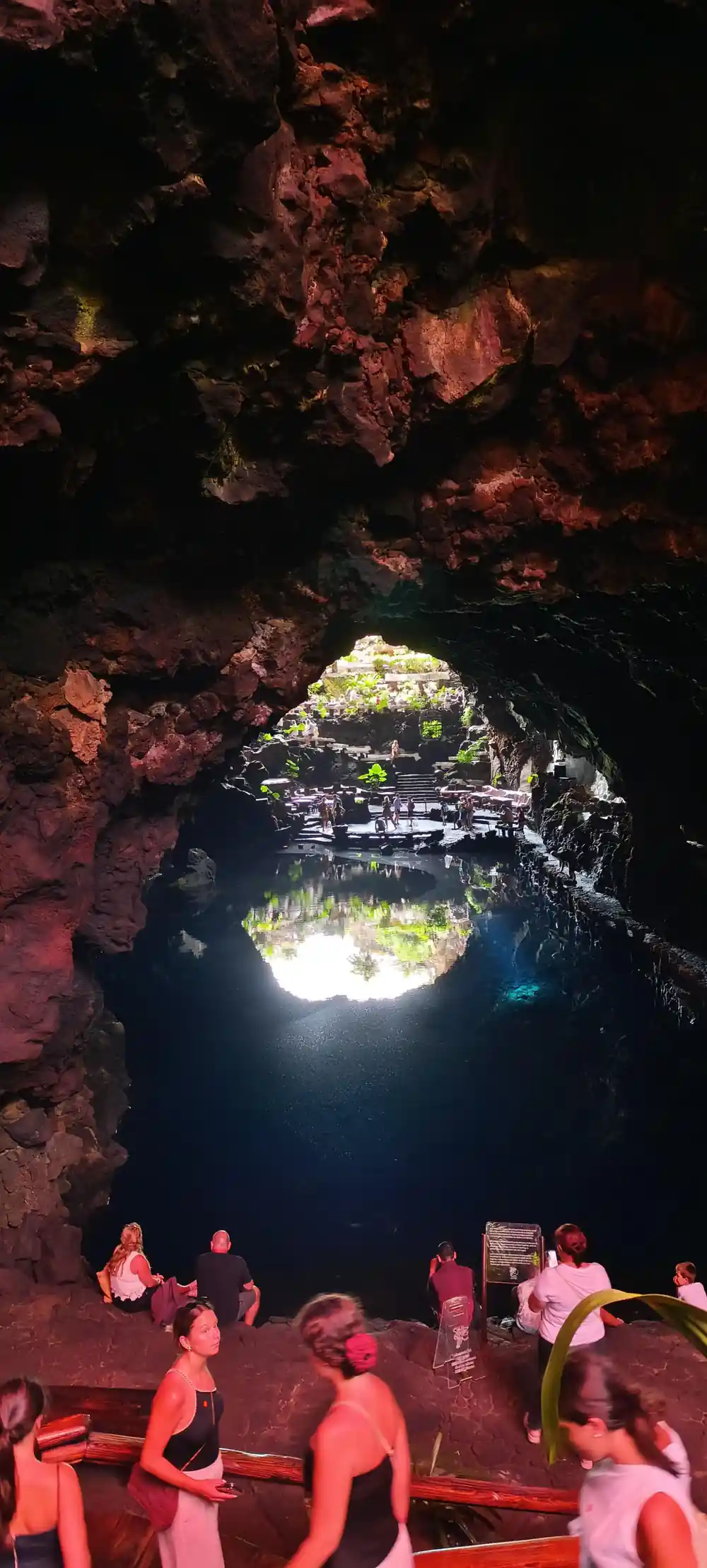 Cave chamber with bright red-lit rock formations and many people