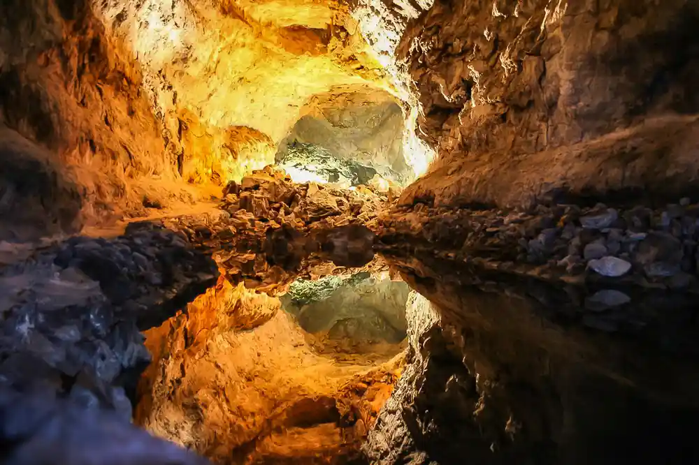 Cave interior with golden rock walls and water reflection