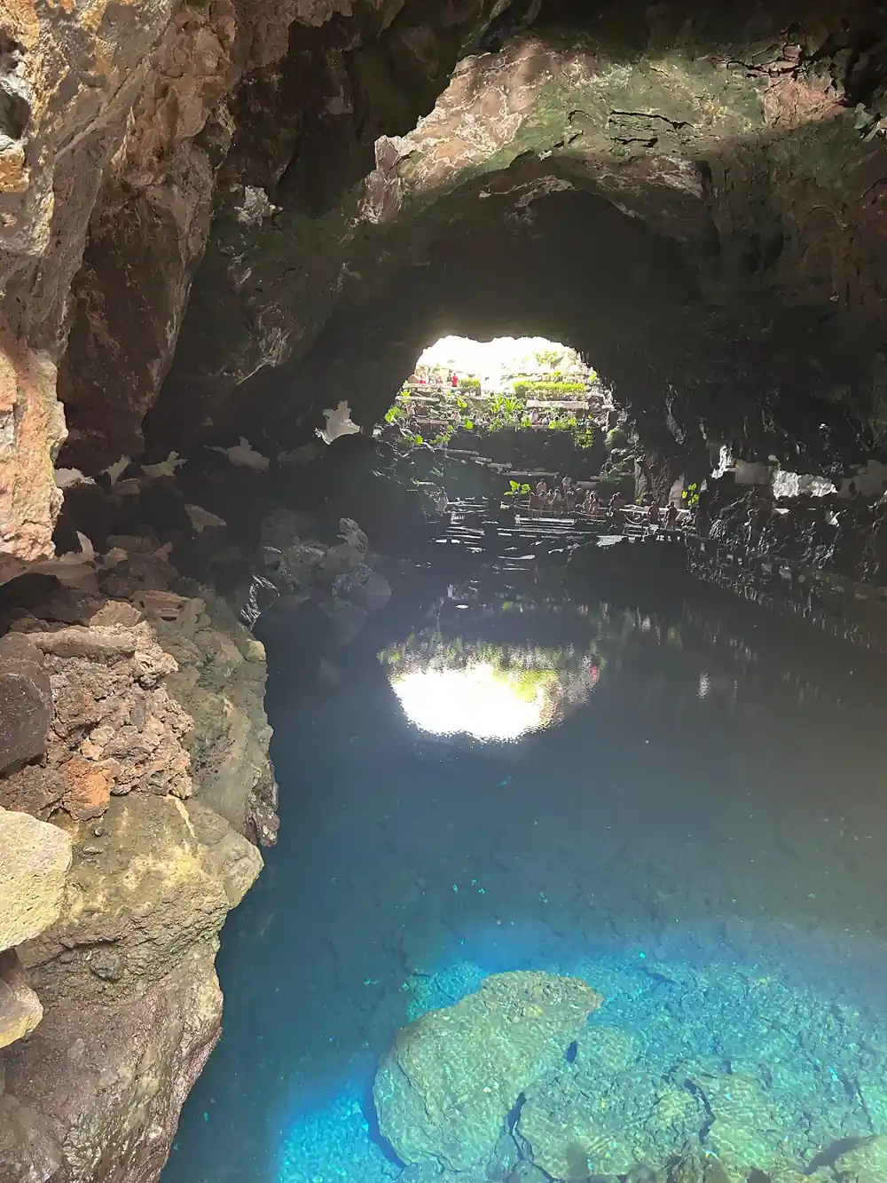 Cave opening above bright blue water with visitor platforms