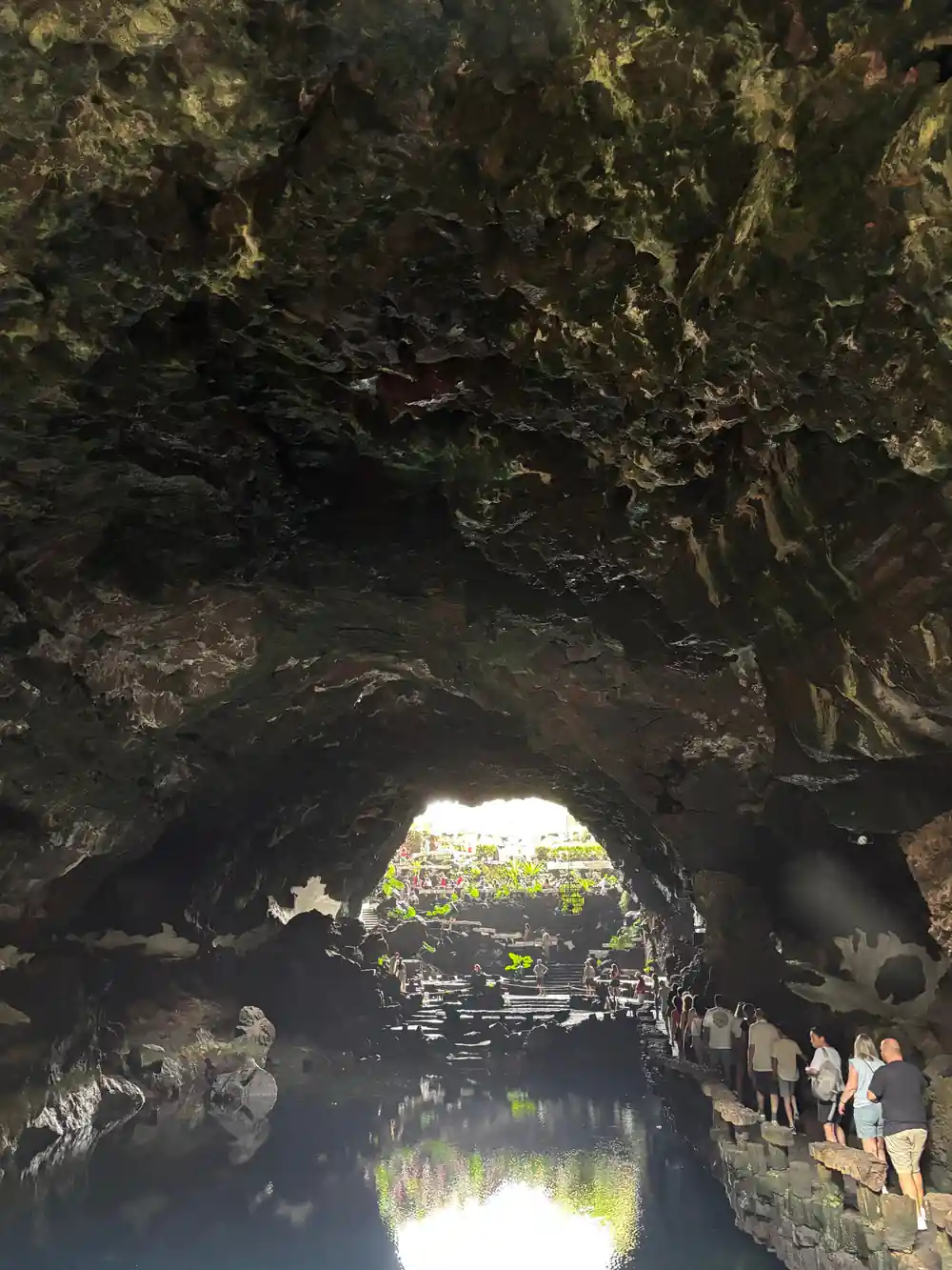 Cave passage with reflective water and crowd of tourists