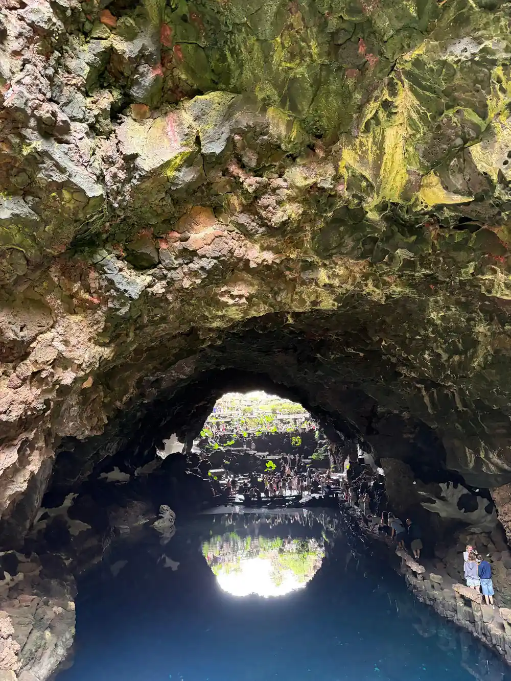 Cave tunnel opening with bright light and water reflection