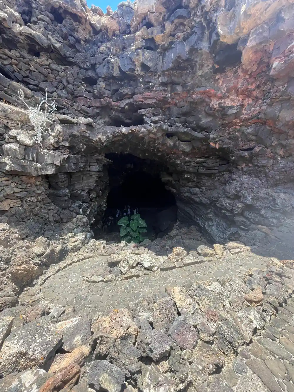 Dark cave entrance in colorful volcanic rock formation