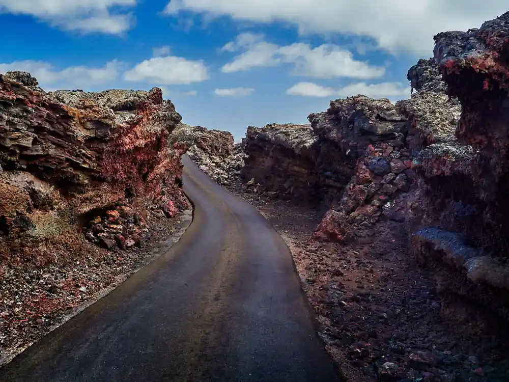 Dark road winding through red volcanic rock formations