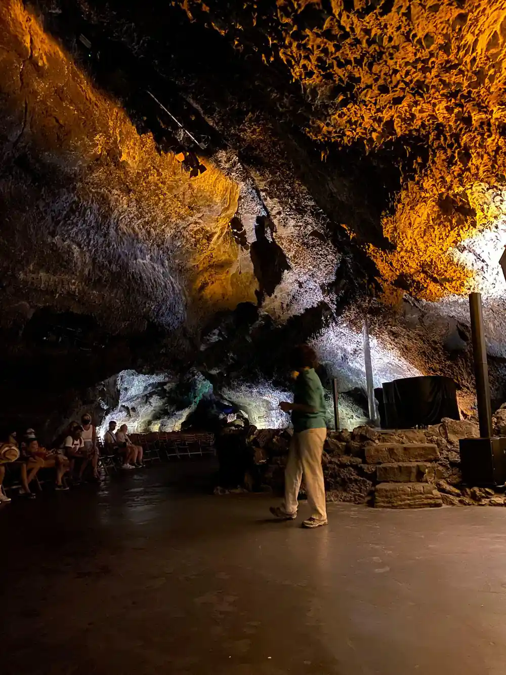 Large cave chamber with golden rock and tourists below