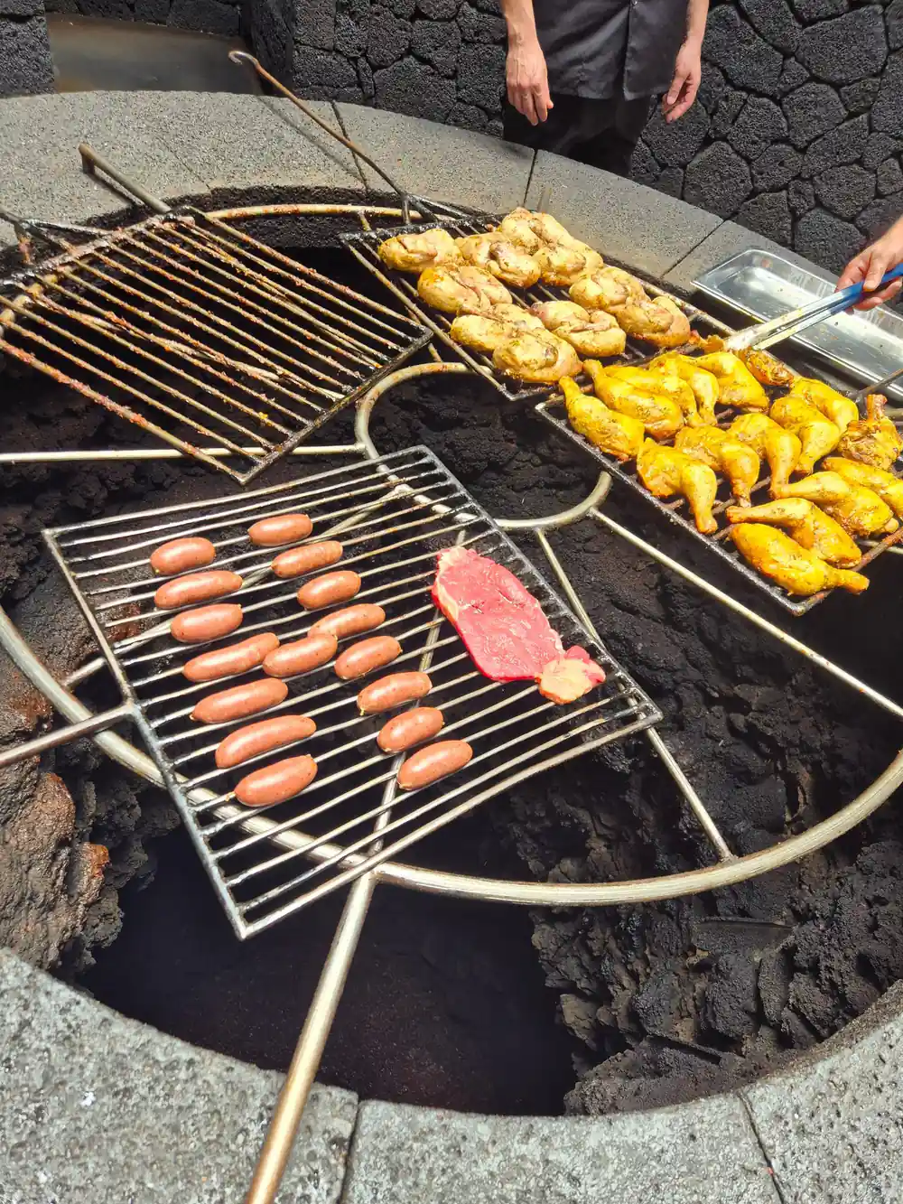 Meat and corn cooking on grill over volcanic heat vent