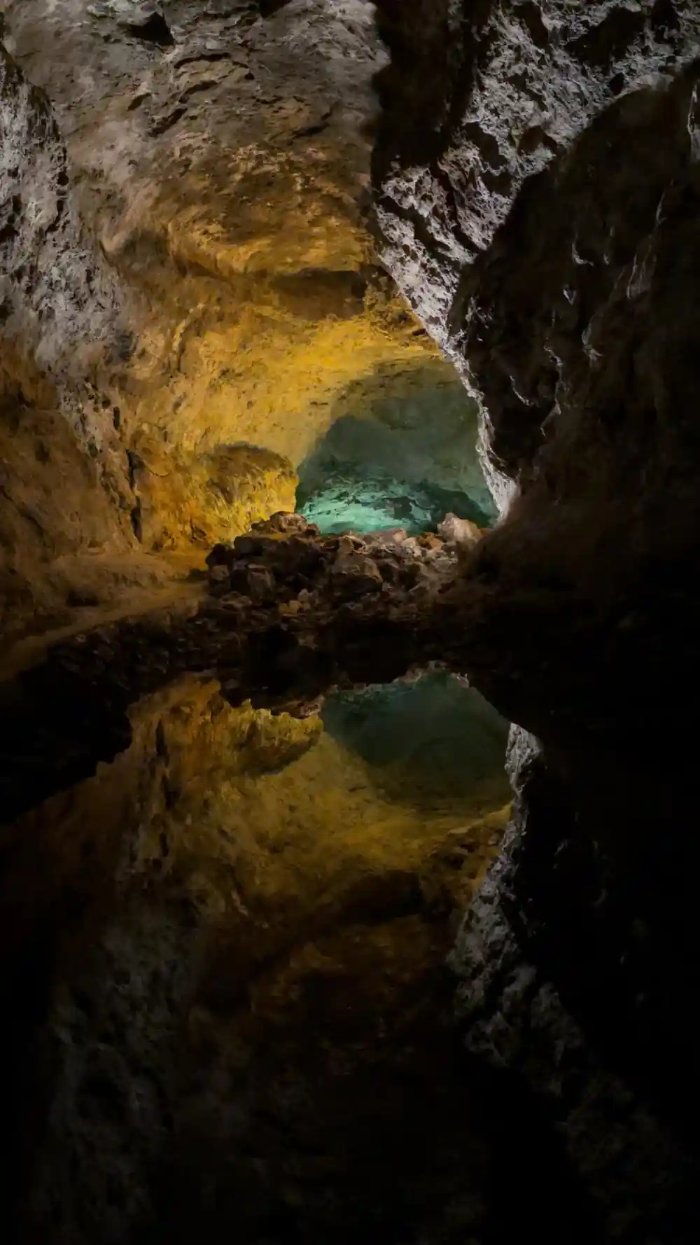 Turquoise hot spring pool nestled between dark volcanic rock formations