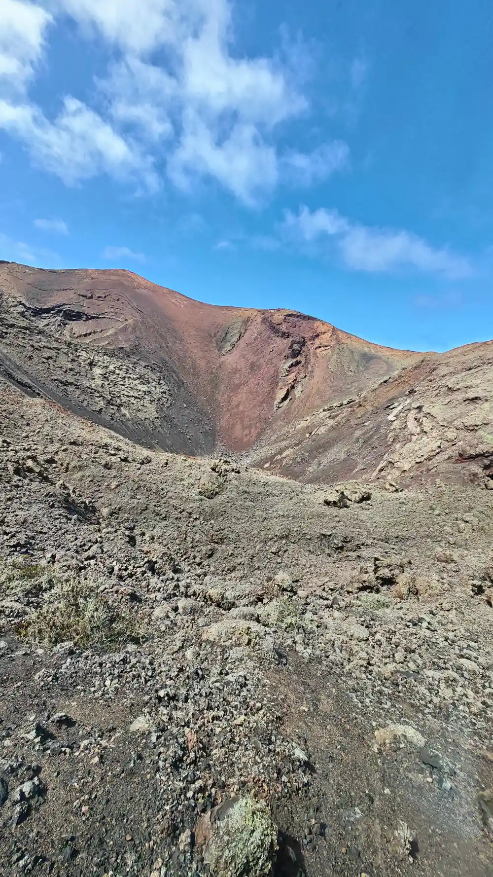 Volcanic crater with reddish rock formations and sparse vegetation