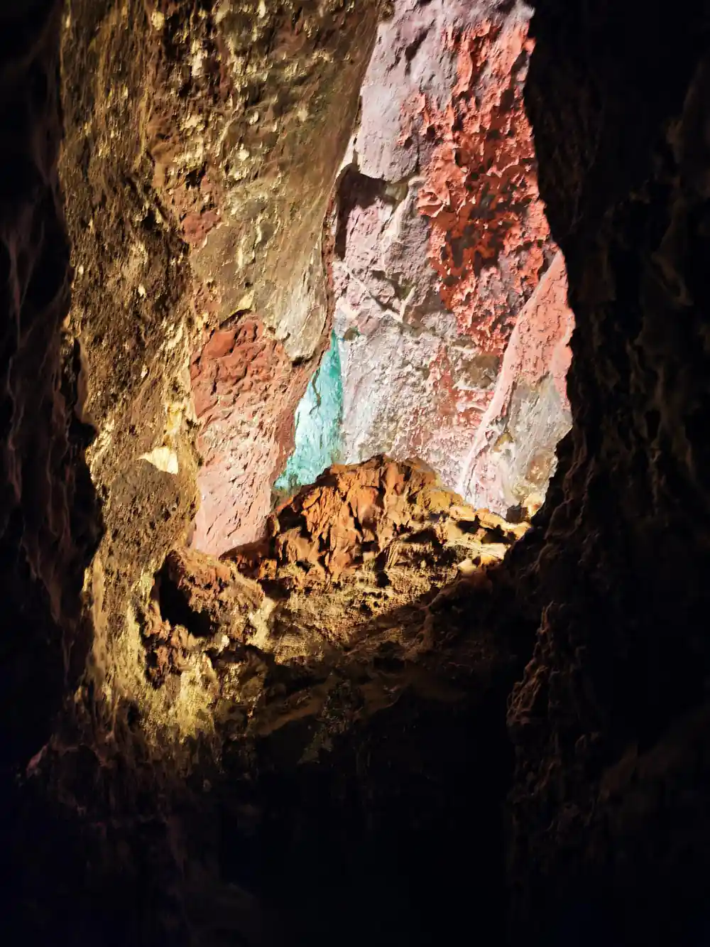 Woman's hand touching colorful mineral deposits inside dark cave