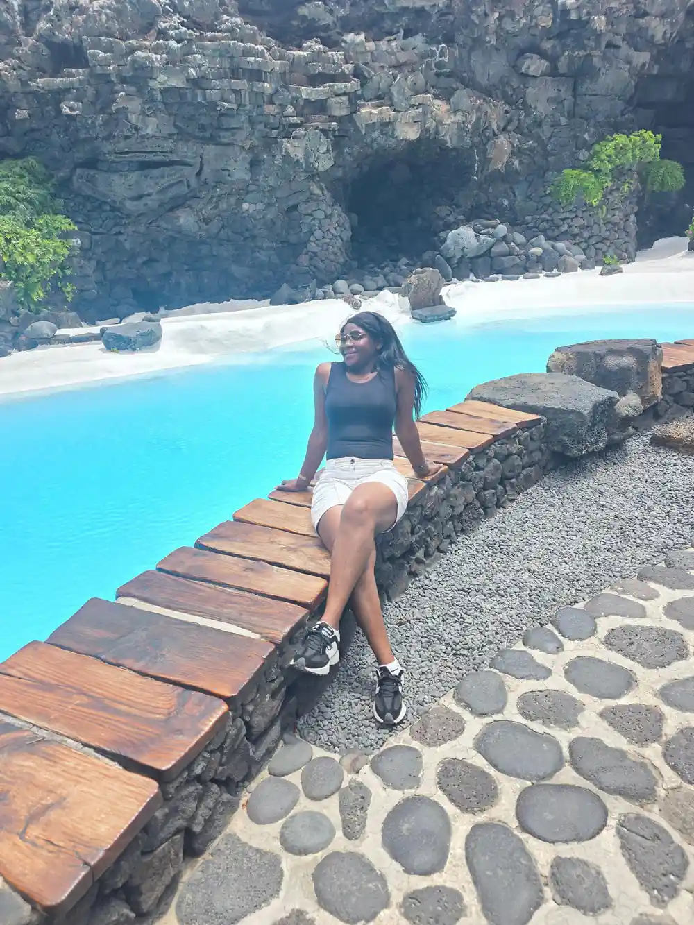 Woman sitting on wooden deck by bright turquoise water