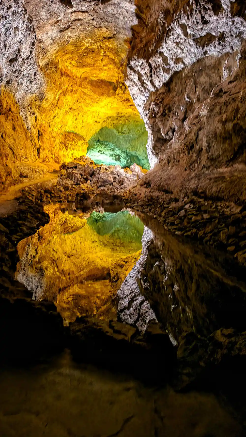 Yellow-lit cave chamber with turquoise water below